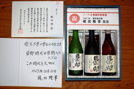 左上 ： フェロー称号記 右　　： 埼玉大学ブランド清酒「鳳翔閣」 左下 ： 梶田隆章先生直筆色紙