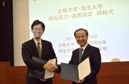 協定書を披露し笑顔で固い握手を交わす山口学長と吉岡総長