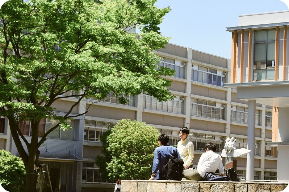 埼玉大学キャンパス内の一コマ。埼玉大学図書館前で3人の男子学生がおしゃべりをしている。